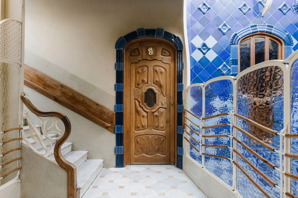 Decorative wooden door with intricate design, flanked by colorful tiles and a staircase in an artistic entranceway.