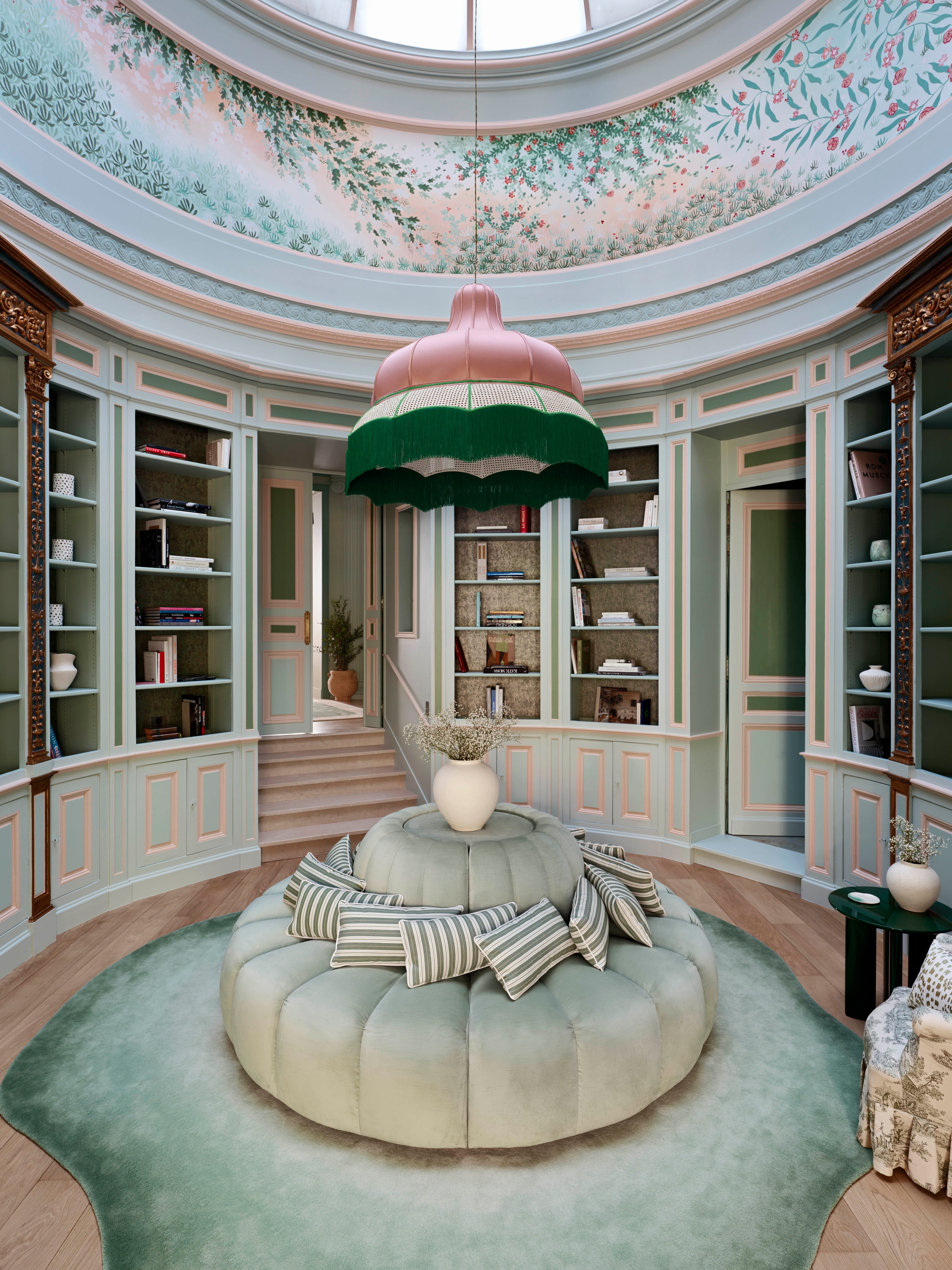 Elegant interior featuring a plush round seating area and a dramatic pendant light, with a pastel-color scheme.