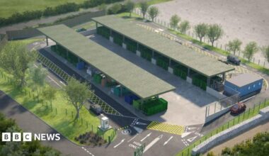 An artist's impression of a recycling centre which has two rows of different colour containers for waste. Both rows are covered with a green canopy and there are spaces to park cars. Trees are planted around the site.