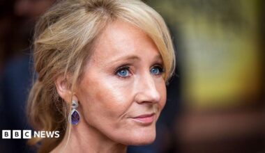 A woman - JK Rowling- with blonde hair, wearing tear drop shaped earrins, viewed side on