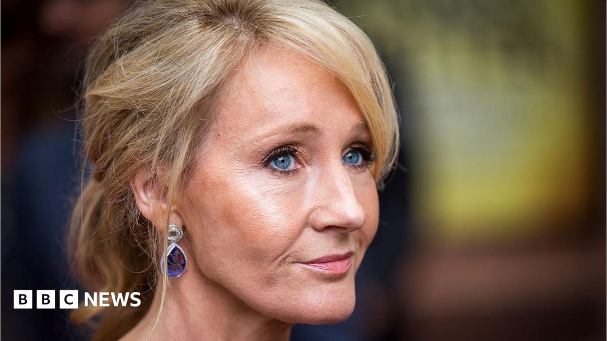 A woman - JK Rowling- with blonde hair, wearing tear drop shaped earrins, viewed side on