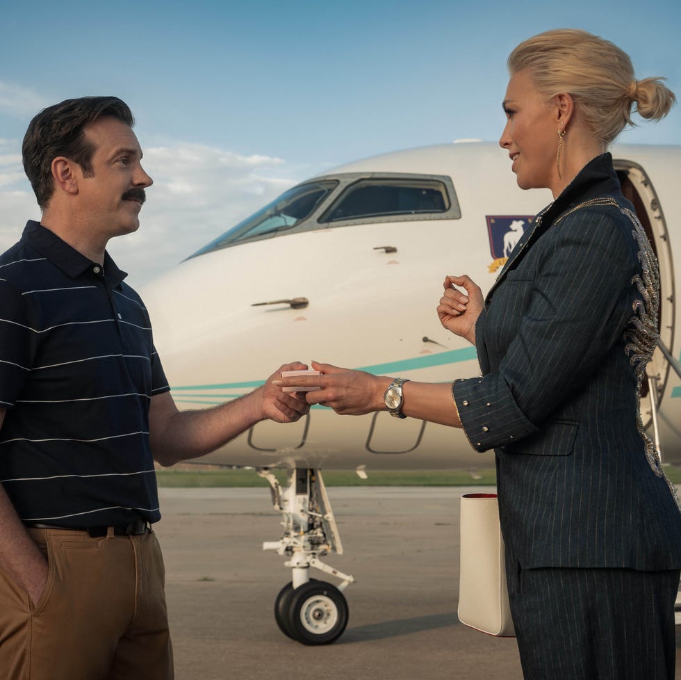 two people exchanging an envelope beside a jet on the tarmac. two people exchanging an envelope beside a jet on the tarmac.