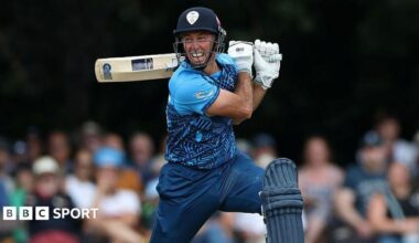 Wayne Madsen in blue Derbyshire Falcons kit holds his bat horizontally behind his head after playing a shot