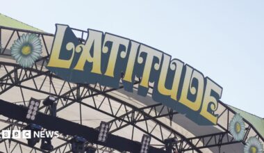 A close-up of the Latitude Festival sign on the top of a stage at the event. The letters are in block capitals, edged in black and coloured yellow fading to cream. Above it is sky.