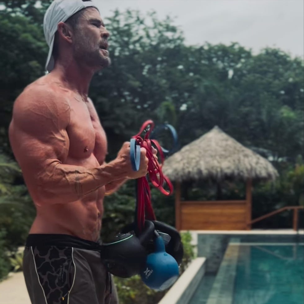 person exercising with kettlebells and resistance bands by a pool.