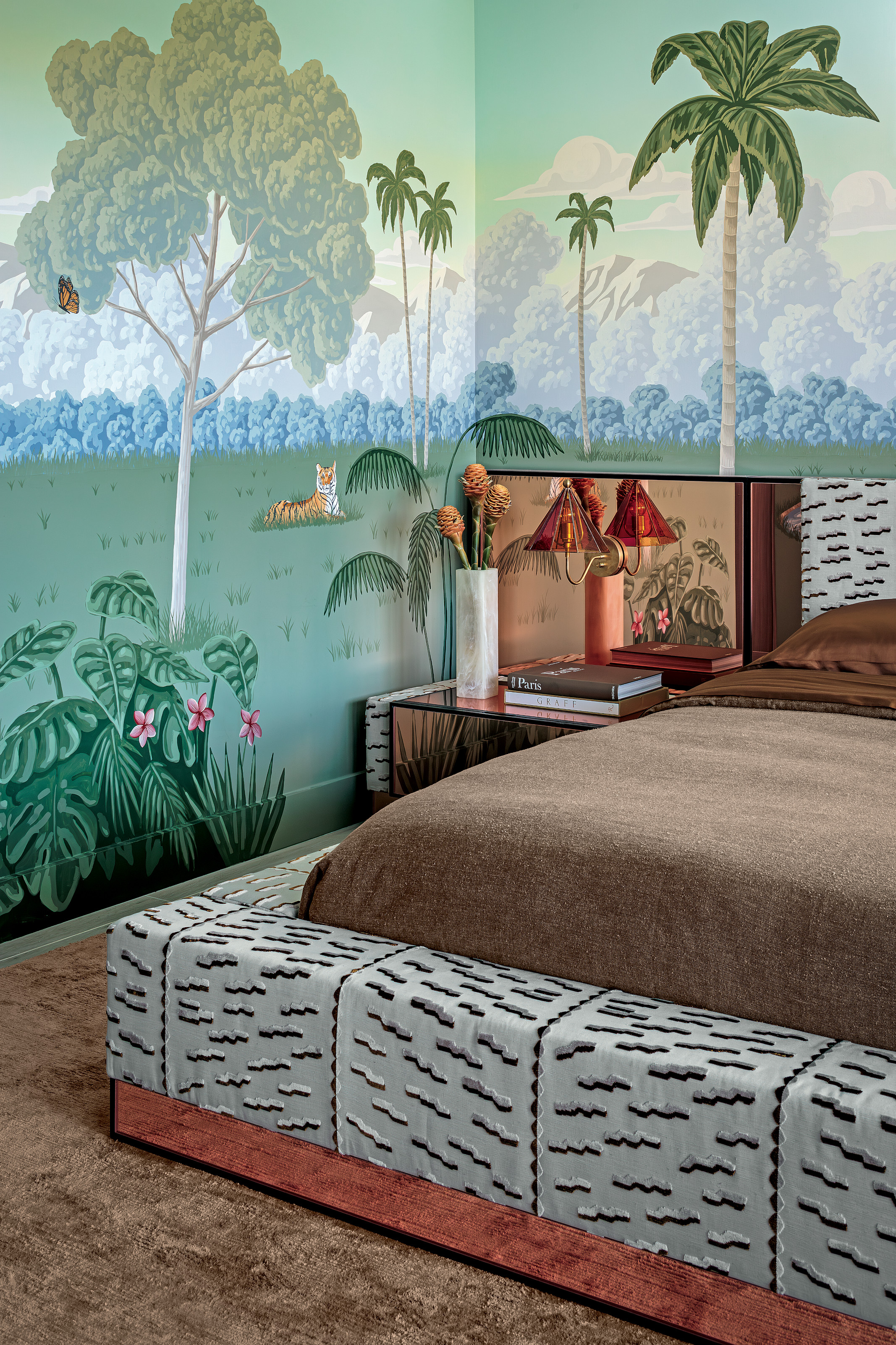 Bedroom with hand-painted animal mural, brown carpet, oversized bed upholstered in black and grey fabric, brown bed linen