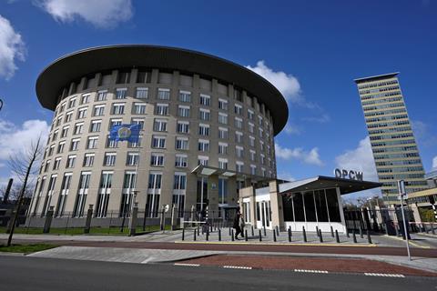 In the Hague, the headquarters of the OPCW with a sign and flag on a circular office building with seven floors.