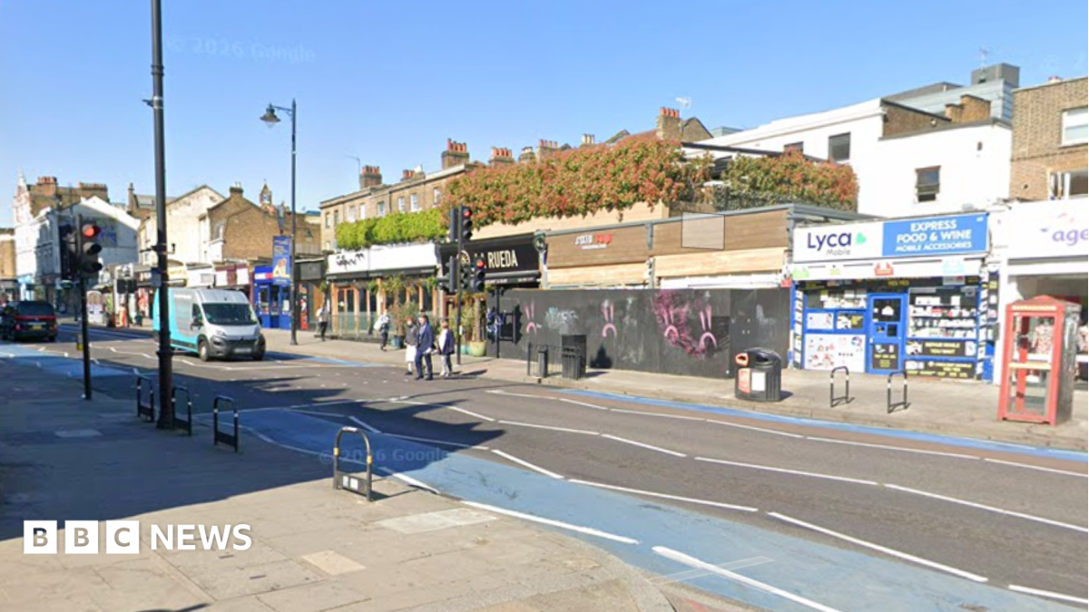 A screenshot from Google Streetview shows a view of shops on Clapham High Street, close to Tremadoc Road. The archive picture shows people crossing the street as a van waits at traffic lights