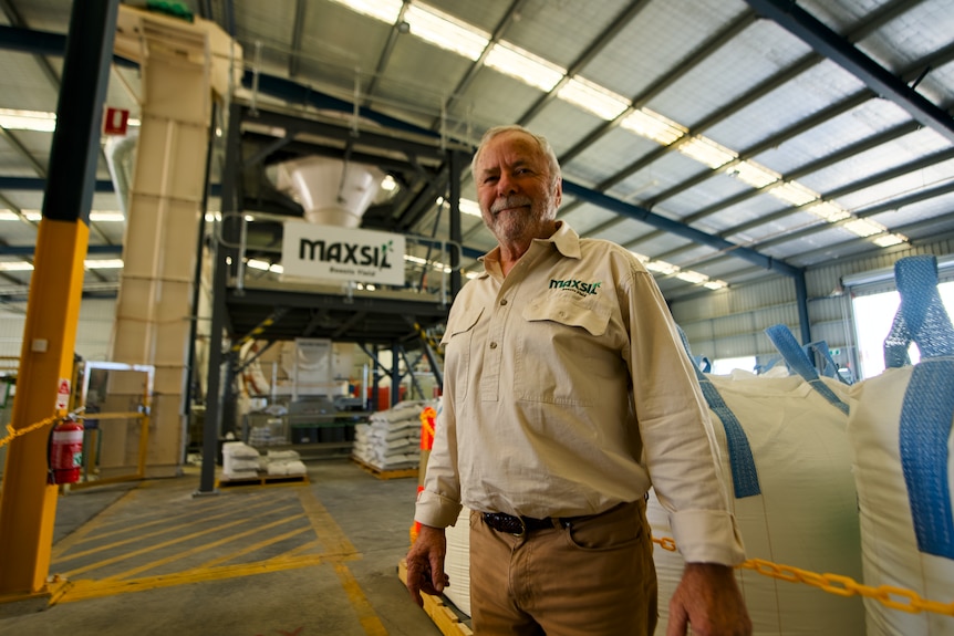 A man standing in front of large white bags in a factory.