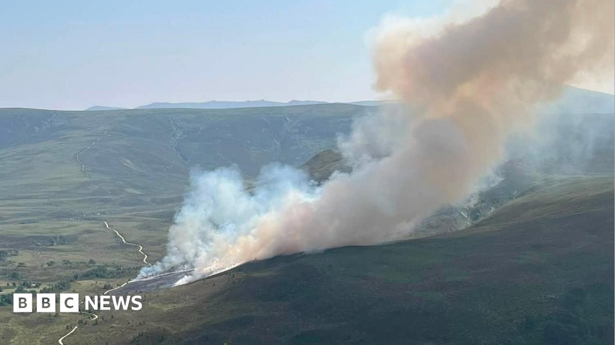 A green hill landscape with plumes of white smoke billowing into the air
