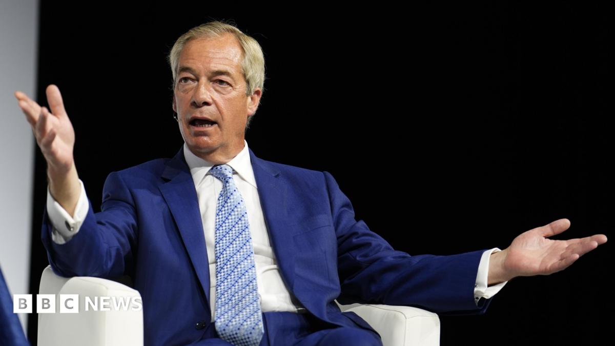 Nigel Farage wearing a blue suit and light blue patterned tie. He is sitting on a white chair.