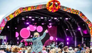 Crowds in front of the Camp Bestival stage. A little girl is on somebody's shoulders, her arms aloft.