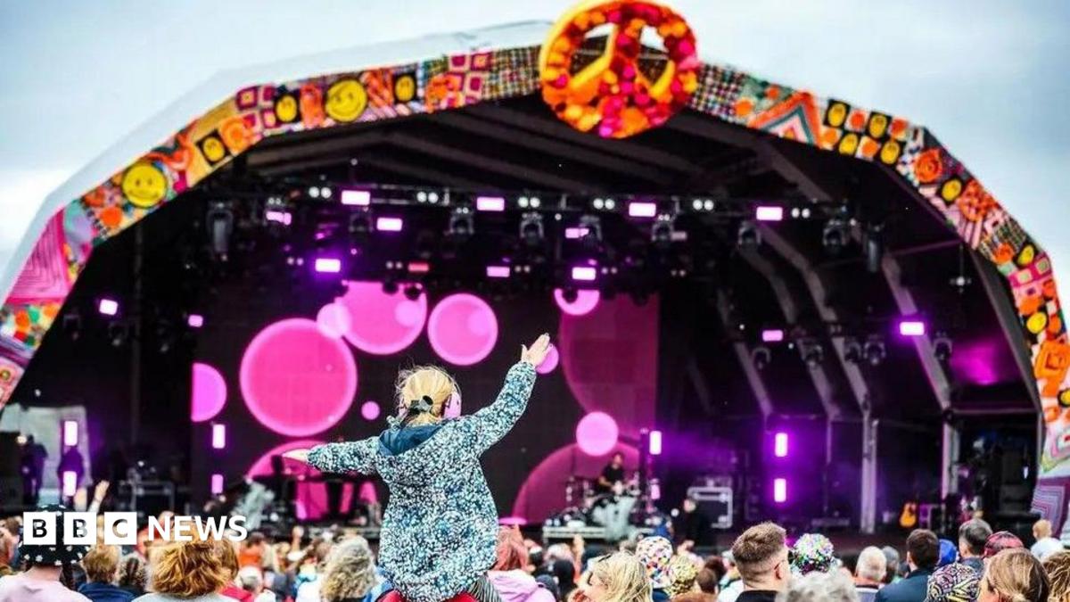 Crowds in front of the Camp Bestival stage. A little girl is on somebody's shoulders, her arms aloft.