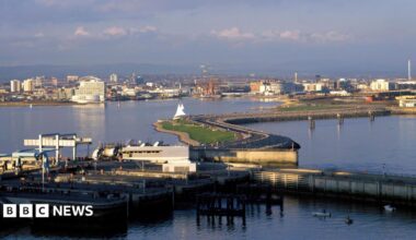 An aerial photo of Cardiff Bay barrage on a sunny day, with the city in the background.