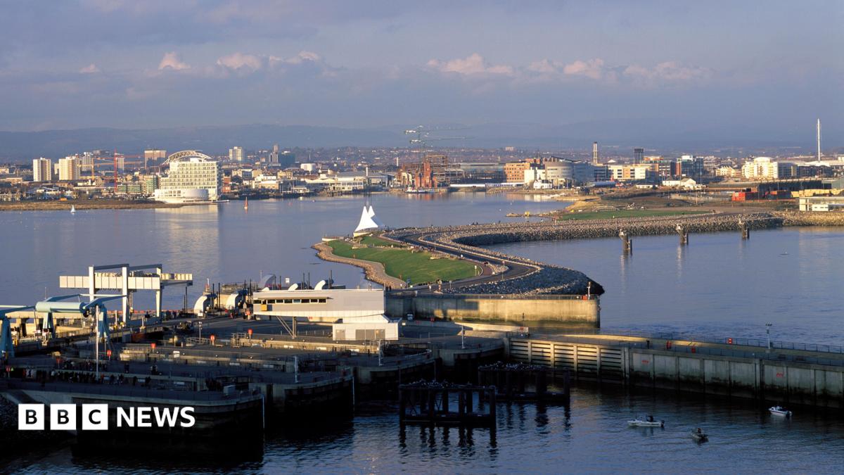 An aerial photo of Cardiff Bay barrage on a sunny day, with the city in the background.