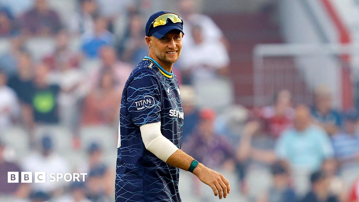 Joe Root in a blue Yorkshire top and cap with sunglasses on his head facing the camera while fielding in a T20 Blast match