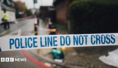 White and blue police cordon tape and the mess on the street in the background, in the place of the crime scene.