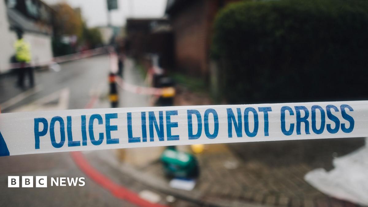 White and blue police cordon tape and the mess on the street in the background, in the place of the crime scene.