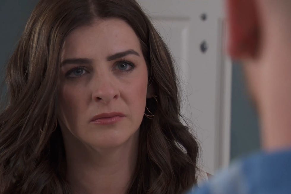 hollyoaks, close up of beth keane with a serious express looking at jonah, who is seen from behind and out of focus on the right side of the frame