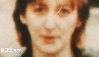 An old and blurry film photo of a women's face. She has brown hair.