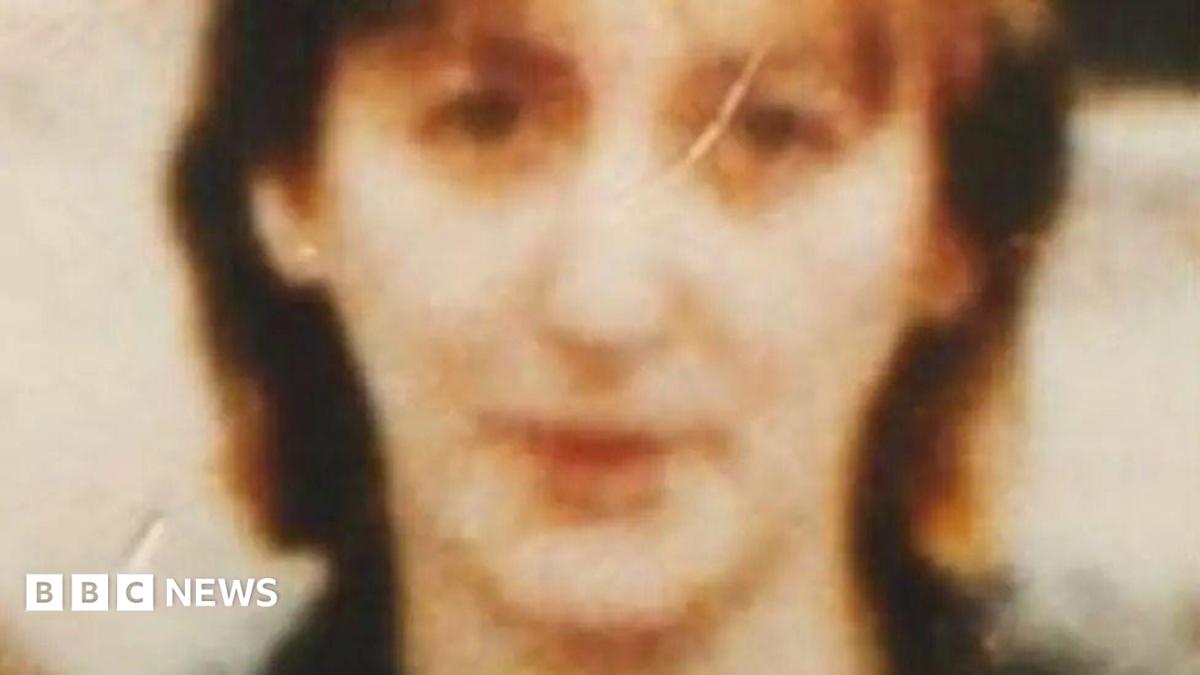 An old and blurry film photo of a women's face. She has brown hair.
