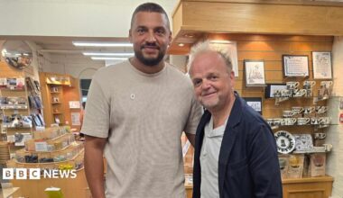Ben Miller, a man with short dark hair, a beard and a beige shirt, stands next to actor Toby Jones, who is wearing a white shirt and dark blue jacket. They are both standing in a pottery gift shop.