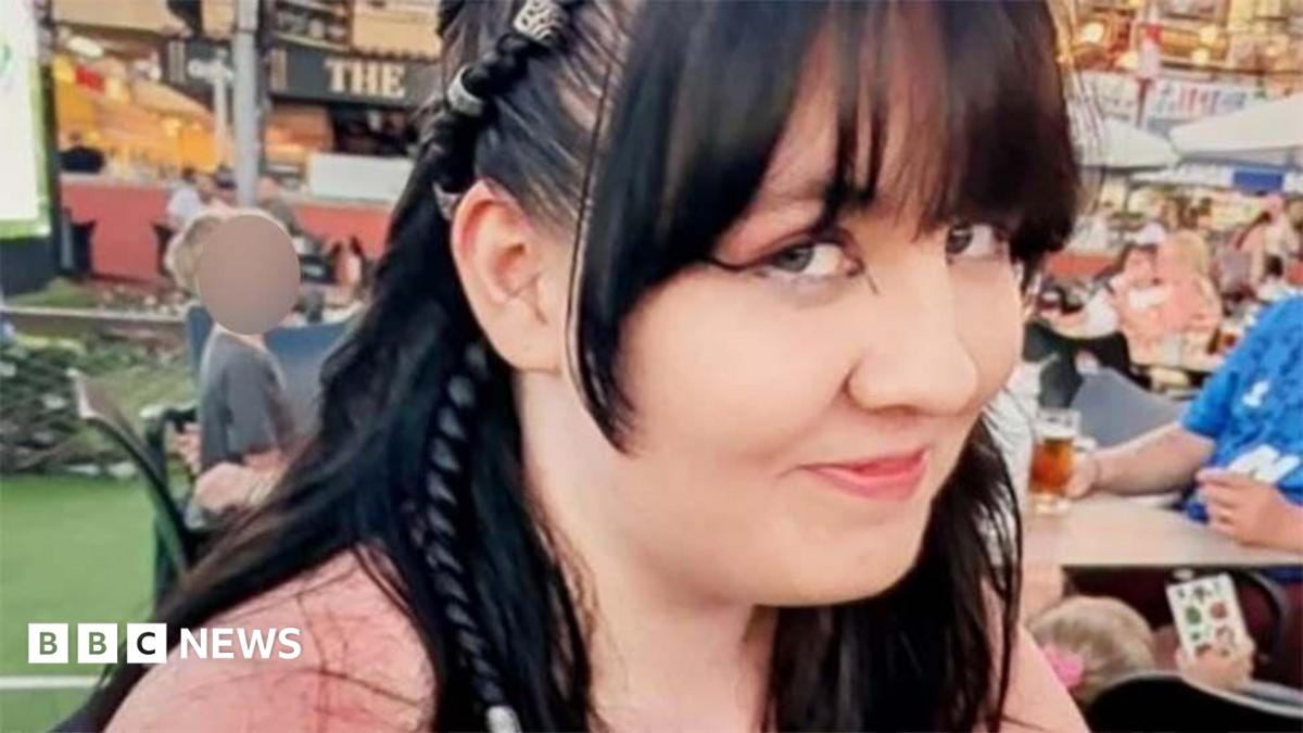 Lilly Jones, who has black hair and is wearing a pink top. She has a fringe and pair of her long hair is tied into a braid.