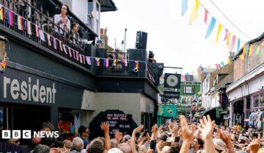 Singer Nick Cave plays a show with his band on the roof of a record shop in Brighton. The street below is swamped with fans.