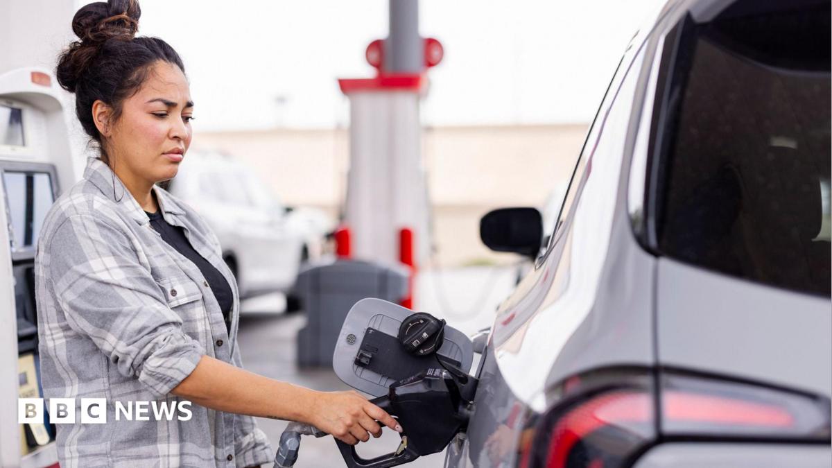 Woman wearing a grey shirt fills up her car at a gas station