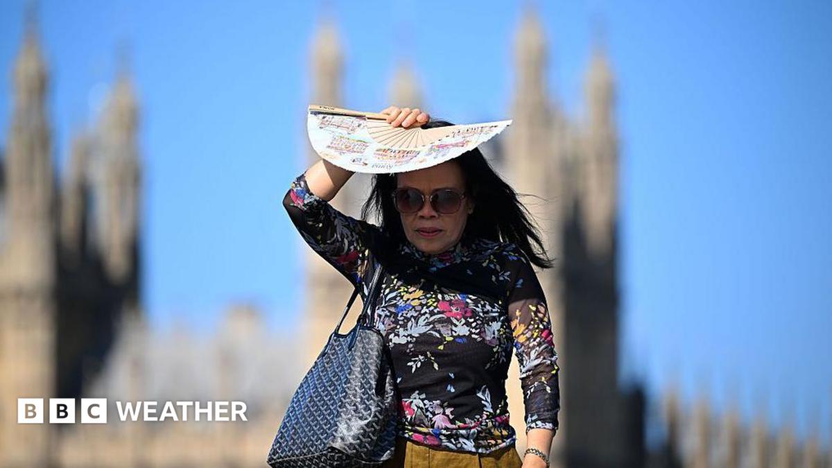 A woman in bright sunlight shades her face with a patterned paper fan