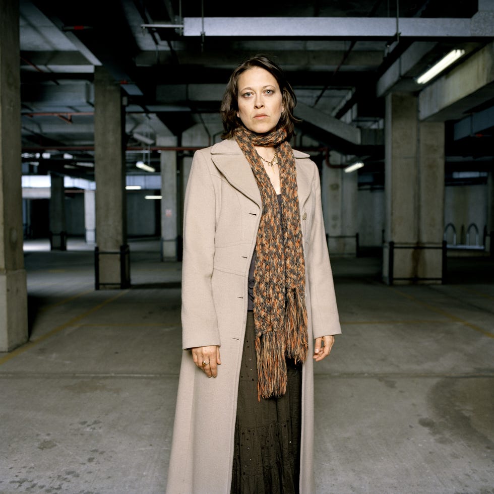 person in a long coat and scarf standing in a dimly lit parking garage. person in a long coat and scarf standing in a dimly lit parking garage.