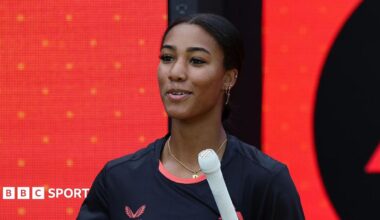 Davina Perrin walks out to bat for Birmingham Phoenix in front of an LED screen featuring the franchise's badge
