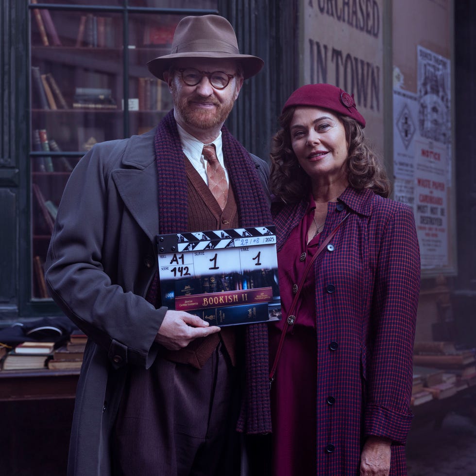 two people in vintage attire holding a film clapperboard in front of a bookstore. two people in vintage attire holding a film clapperboard in front of a bookstore.