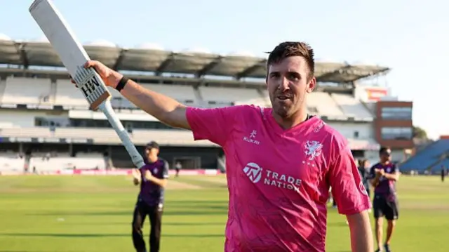 Craig Overton leaves the field with his bat raised aloft in his right hand after Somerset's win at Yorkshire