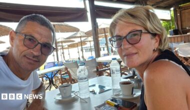 Karovic Ljubisa and his wife Svetlana Grković, smiling for a photo in a bar which appears to be at a holiday resort