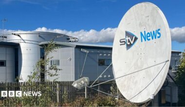 STV News headquarters featuring a large satellite dish, modern architecture, and a clear blue sky with scattered clouds.