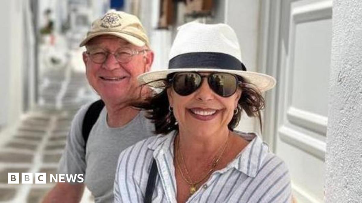 Karen Carter, pictured with her husband Alan. She is wearing dark glasses, a black and white sun hat and a white and striped shirt.