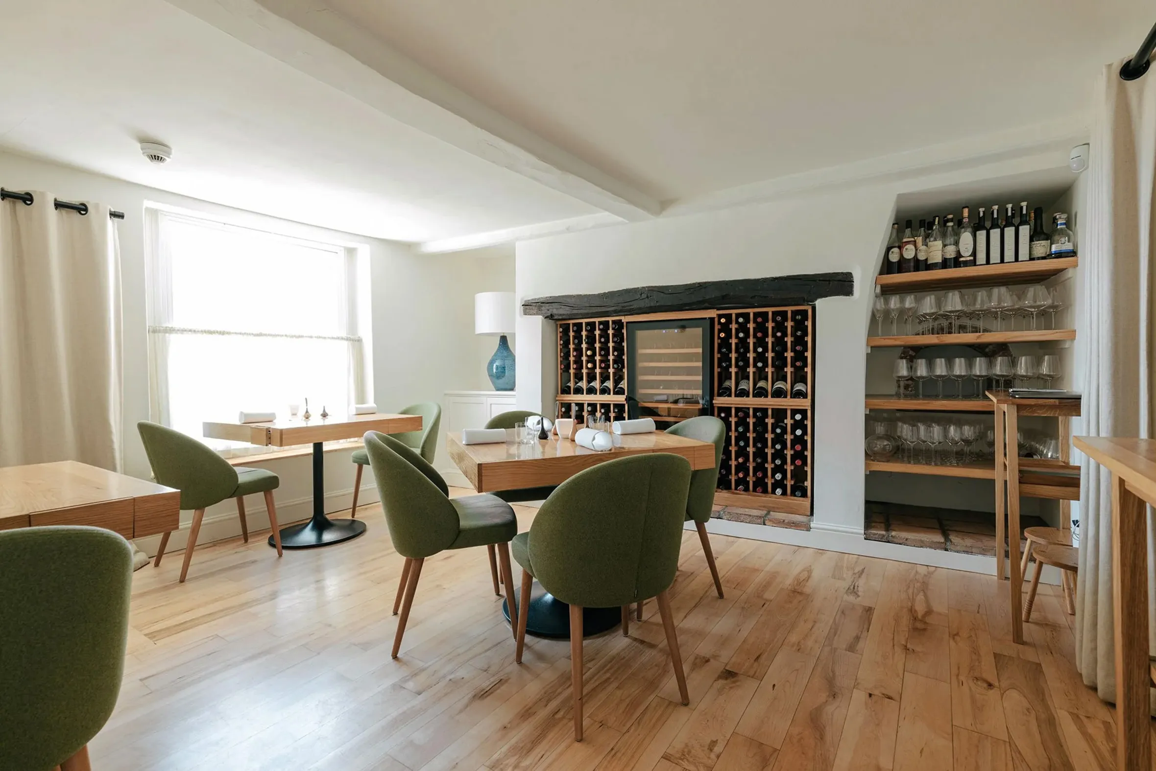 Meadowsweet restaurant dining room with green chairs, wooden tables, and a wine rack.