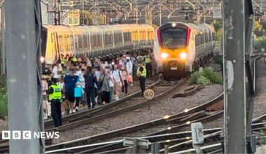 A group of people in single file walk along a train track.