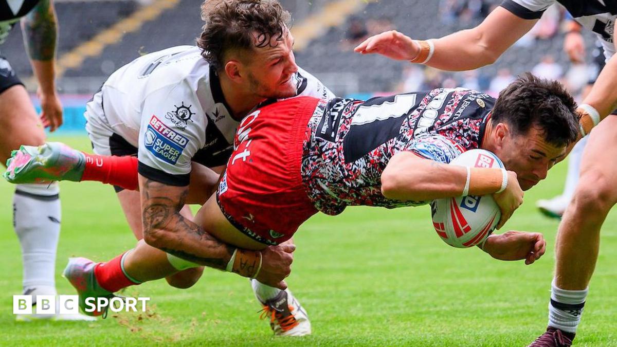 Leigh's David Armstrong, in red shorts and multi-coloured top dives over to score despite a tackle by a Hull FC player, in white shirt.