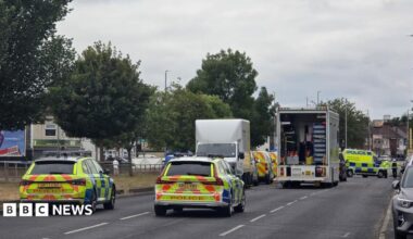 A number of police vehicles close off  dual carriageway in Merseyside. The road has trees lined down the middle