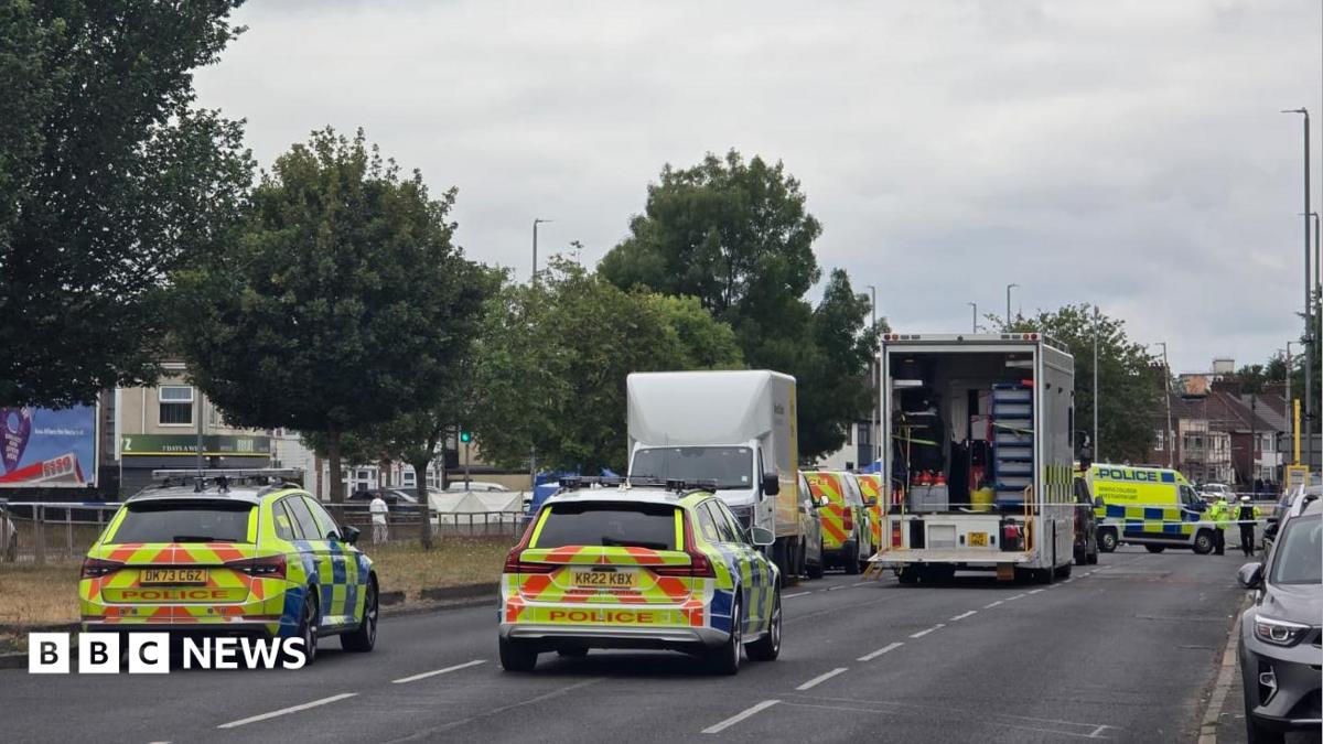 A number of police vehicles close off  dual carriageway in Merseyside. The road has trees lined down the middle