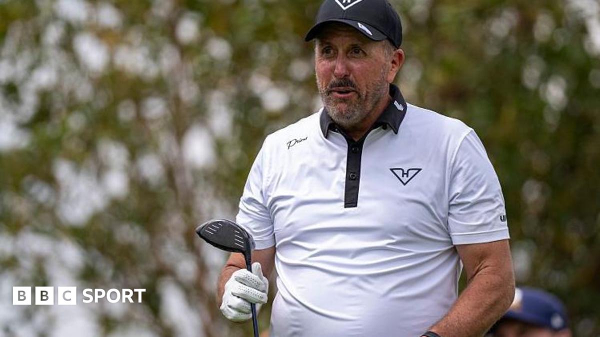 Phil Mickelson with a golf club in one hand, wearing a white shirt