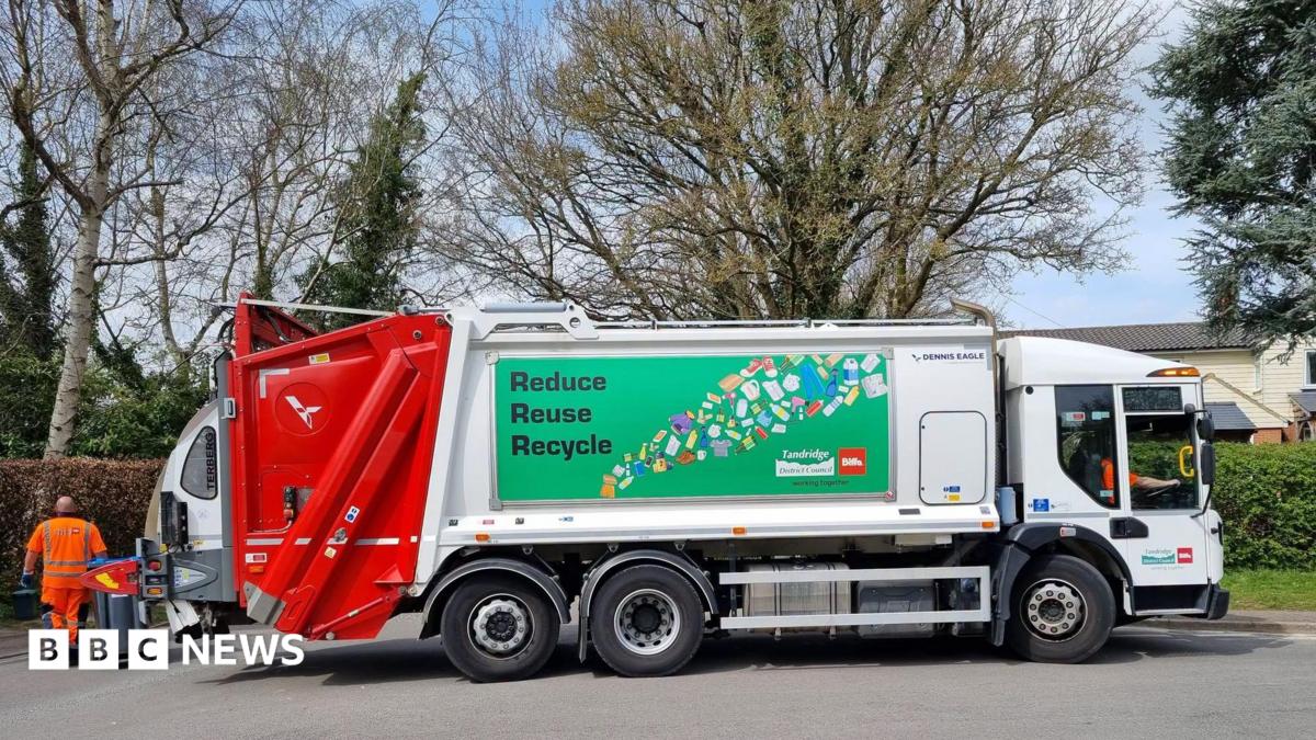 A Biffa recycling lorry is parked on a residential street beside wheelie bins. The vehicle displays a large "Reduce Reuse Recycle" sign and branding from Tandridge District Council and Biffa, with collection staff visible nearby.