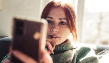 Woman with red hair looking on screen of her mobile phone