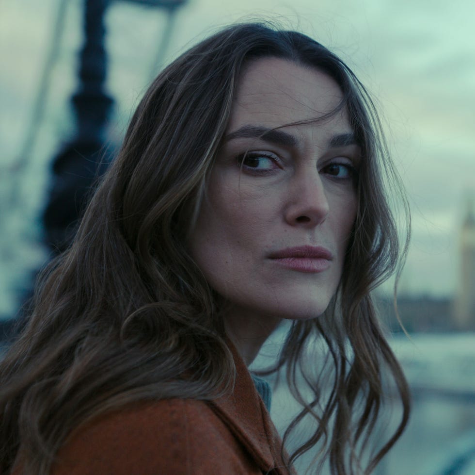 a contemplative woman gazing out at a river and cityscape