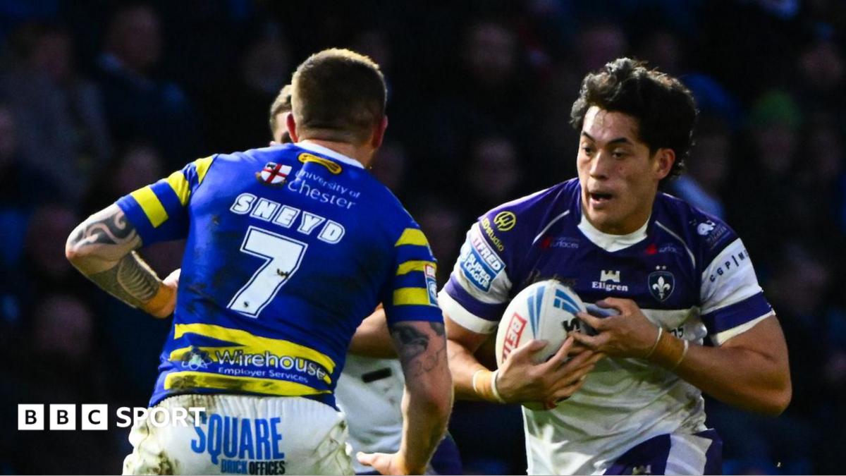 Wakefield's Isaiah Vagana, wearing a white and blue shirt, runs at Warrington's Marc Sneyd