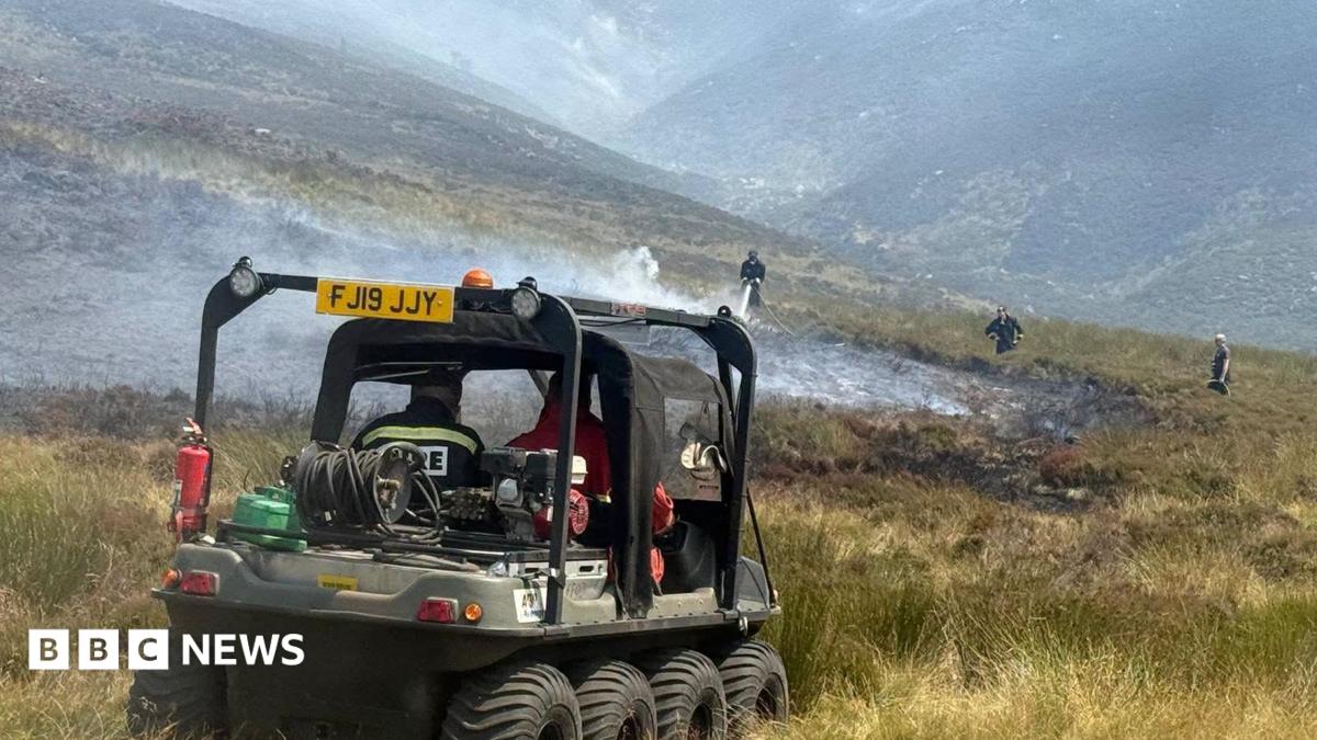 A firefighter damping down hot spots following a moorland wildfire on Tintwistle Moor, above Woodhead Road in Glossop, Derbyshire.