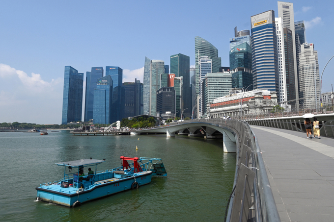 Workers on a barge clear rubbish from the water of Marina Bay in Singapore on July 30, 2025. Photo by AFP