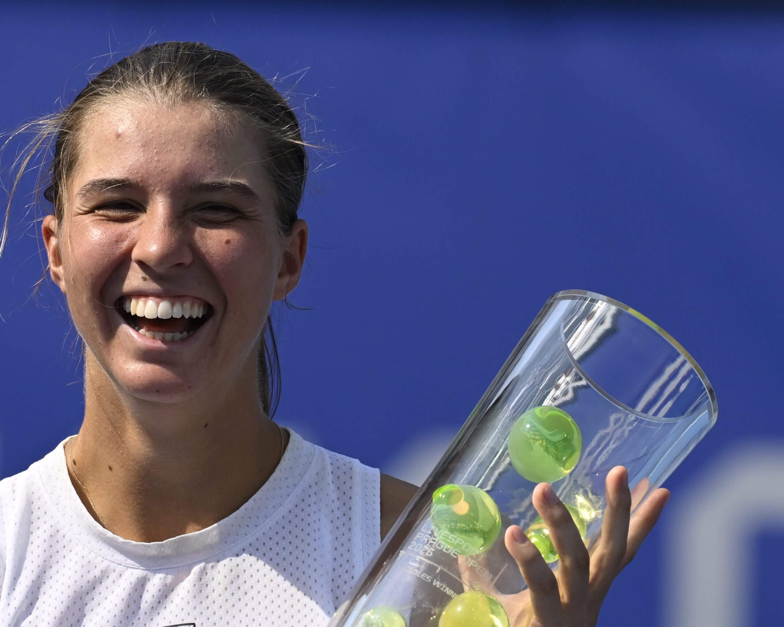 Lilli Tagger smiles holding a glass trophy decorated with tennis balls.